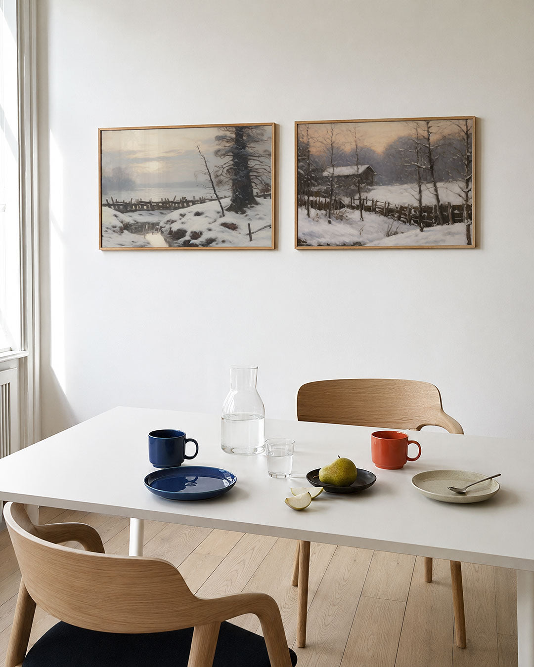 Twee liggende posters met een serene winterlandschap met zachte sneeuwvlakken, aan de muur in een interieur