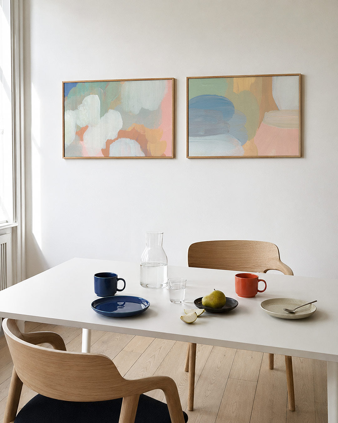 Twee liggende posters met een spel van zachte, vloeiende kleurvlakken in pastelkleuren, aan de muur in een interieur