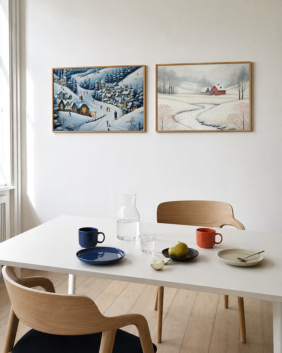 Twee liggende posters met een winterse scène met besneeuwde daken en glooiende heuvels, aan de muur in een interieur