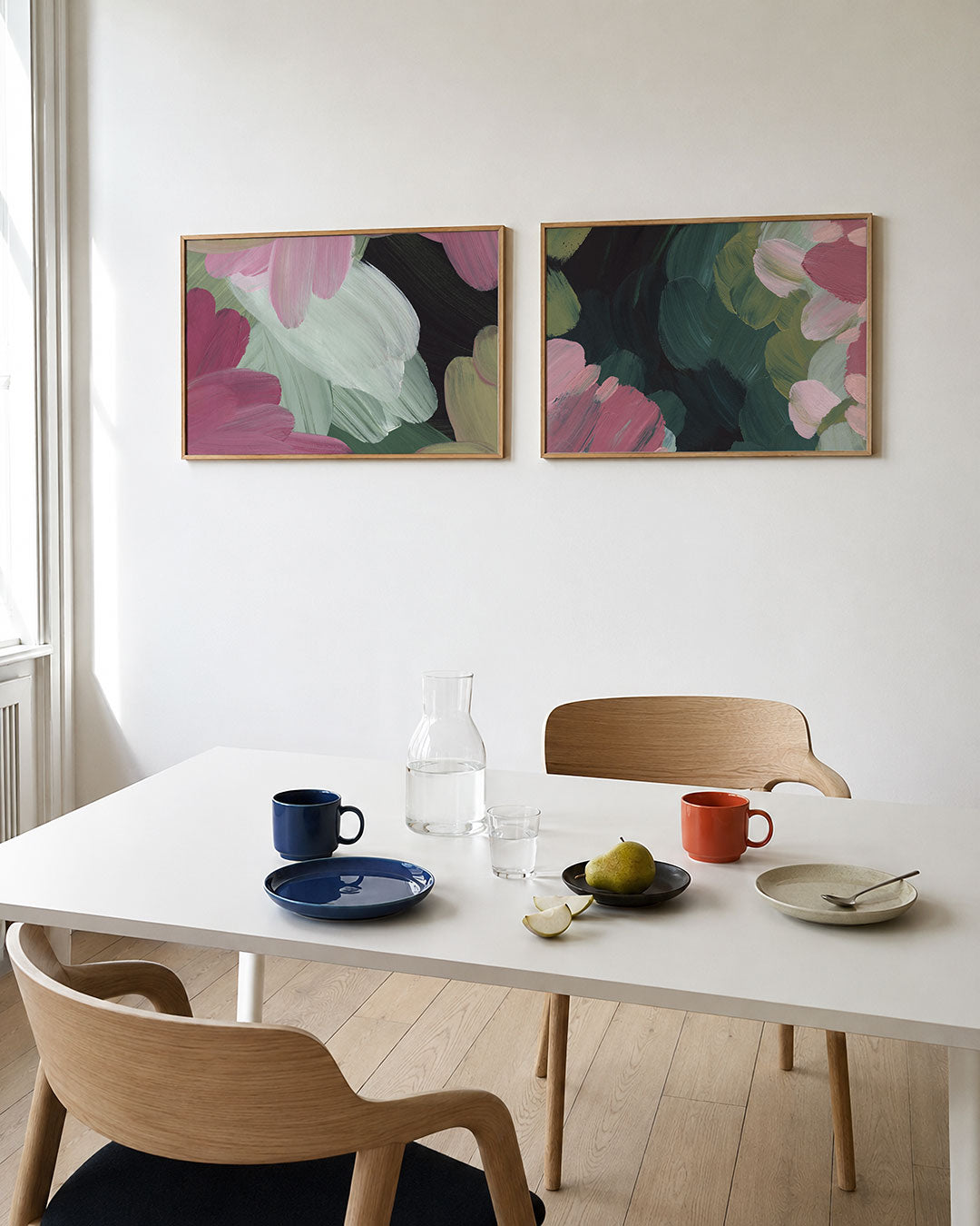 Twee liggende posters met roze, groen en wit, aan de muur in een interieur