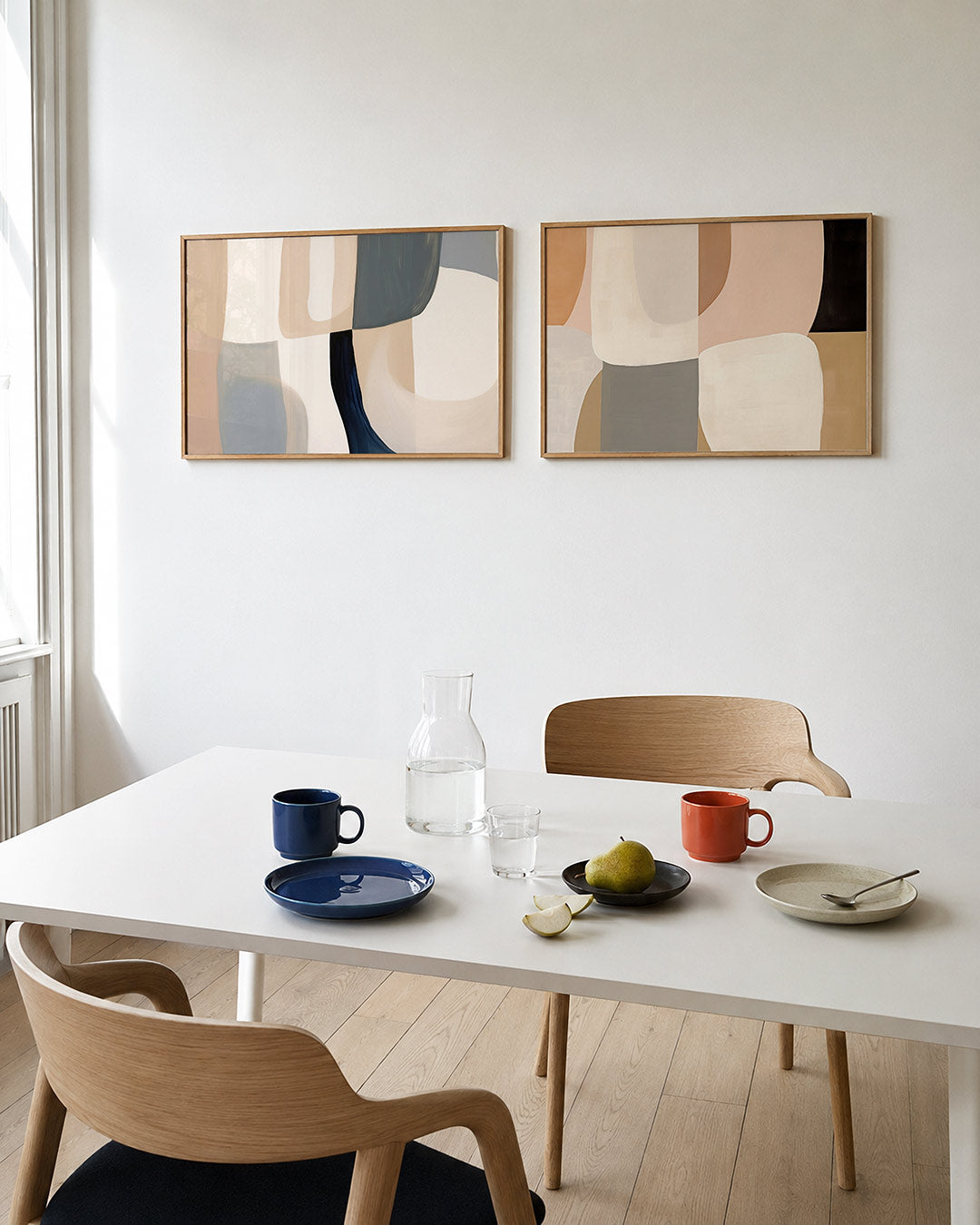Twee liggende posters met zachte, vloeiende vormen in beige, blauw en grijs, aan de muur in een interieur