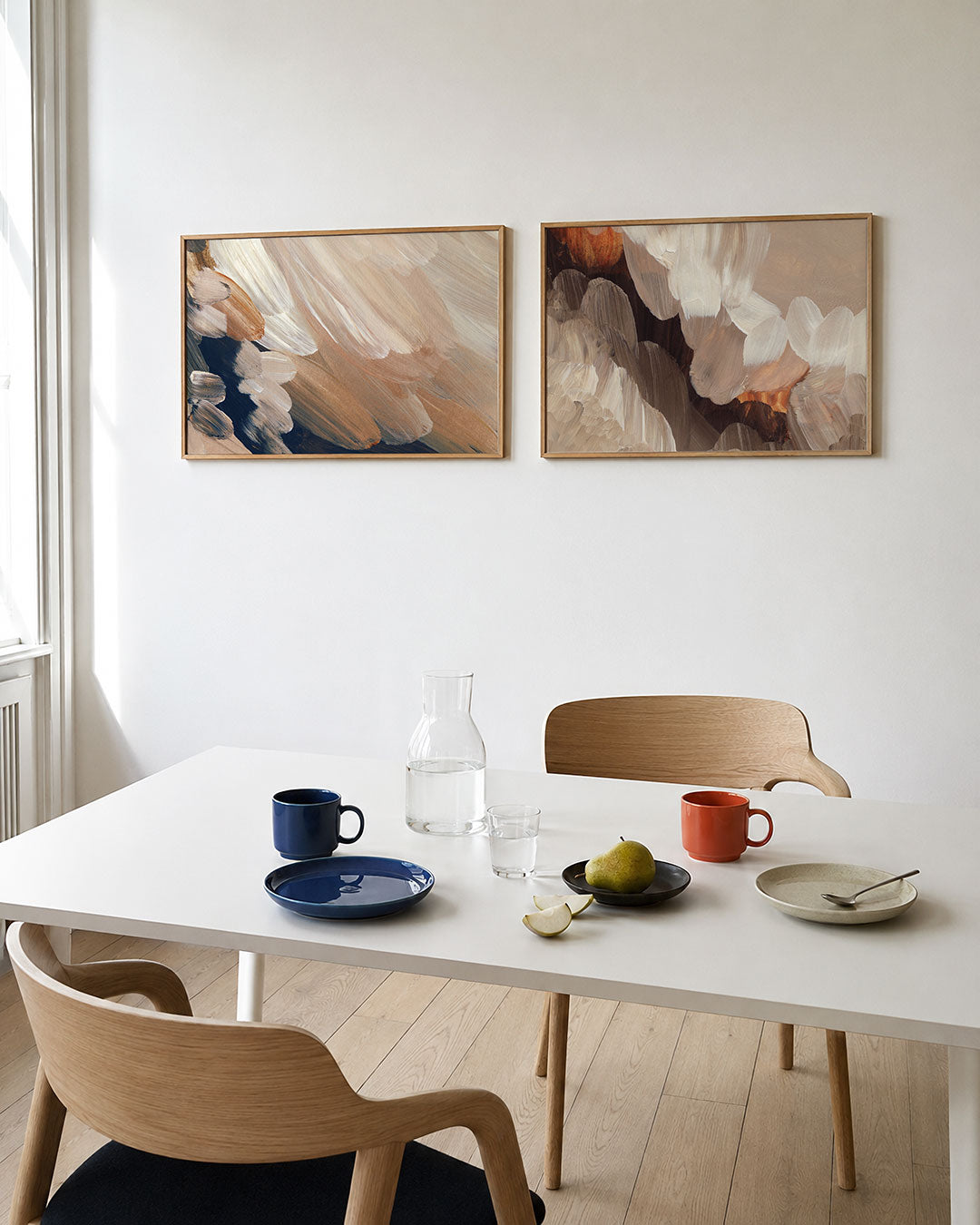Tweedelige posterset met zachte penseelstreken in beige, wit en donkerblauw, getoond in een interieur