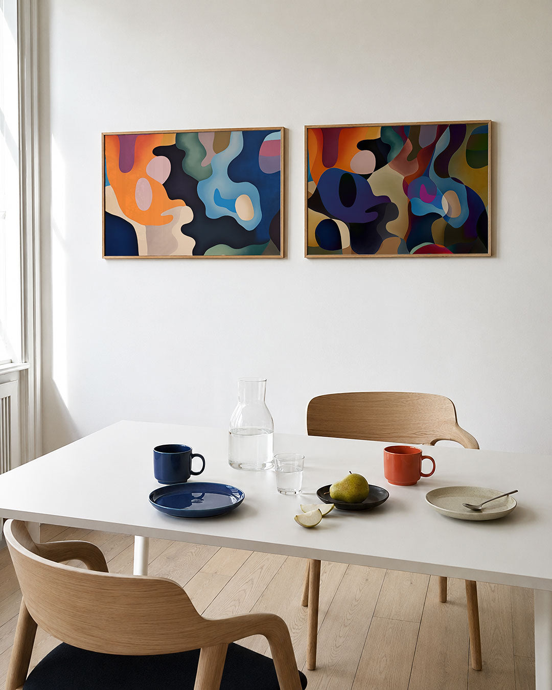 Twee liggende posters met vloeiende vormen en levendige kleuren, aan de muur in een interieur