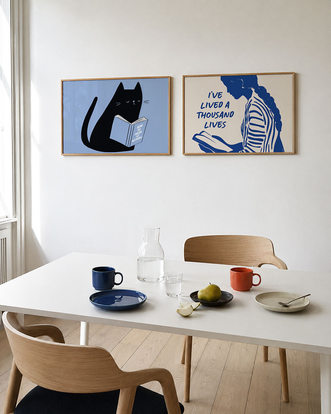Tweedelige posterset met een zwarte kat met een boek op een lichtblauwe achtergrond, getoond in een interieur