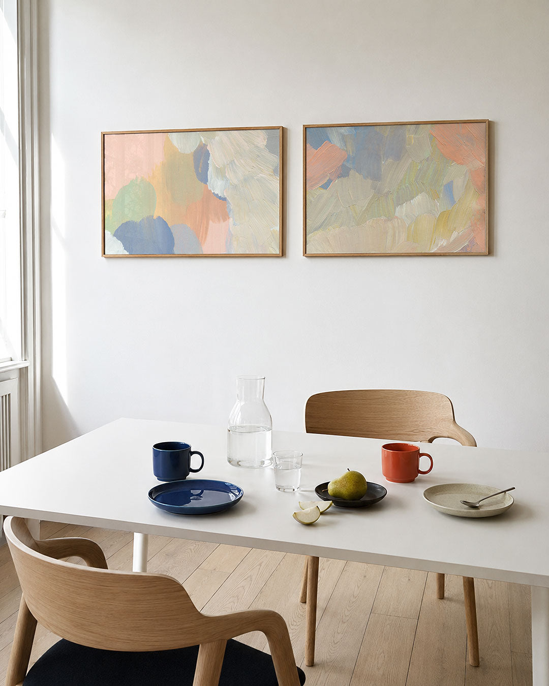 Tweedelige posterset met zachte, pastelkleurige vlakken en vloeiende penseelstreken, getoond in een interieur