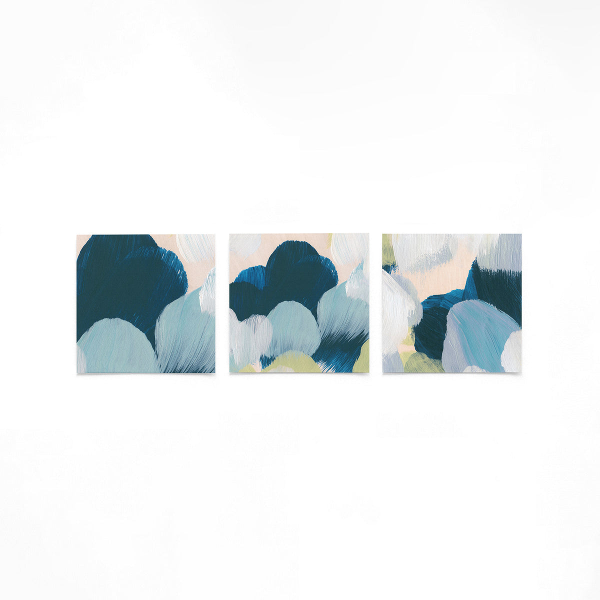Drie vierkante posters met blauwe penseelstreken op een gebroken witte achtergrond