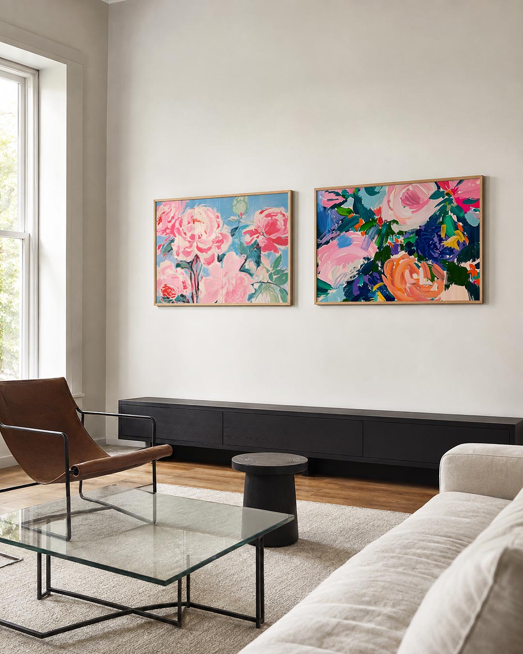 Twee liggende posters met roze en groene bloemen tegen een luchtblauwe achtergrond, aan de muur in een interieur